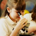 girl looking into microscope